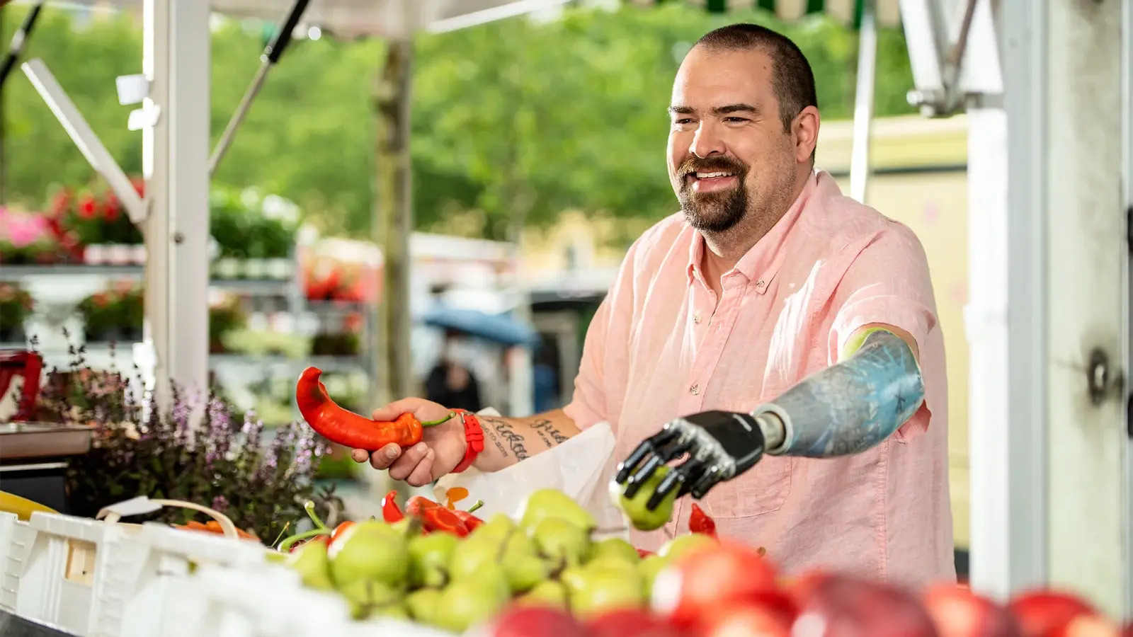 A man holding a pepper with a myoelectric prosthetic hand at a market