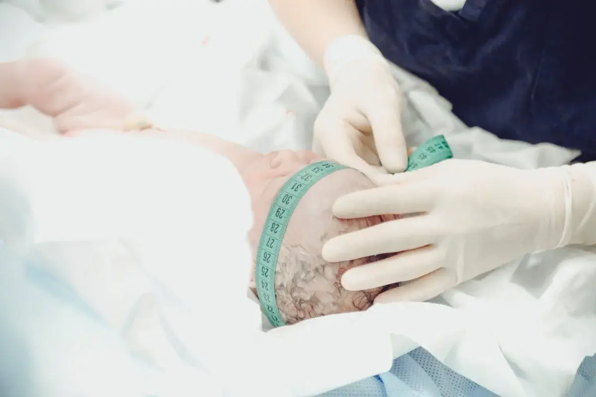 Healthcare professional measuring a newborn baby's head circumference in a clinical setting