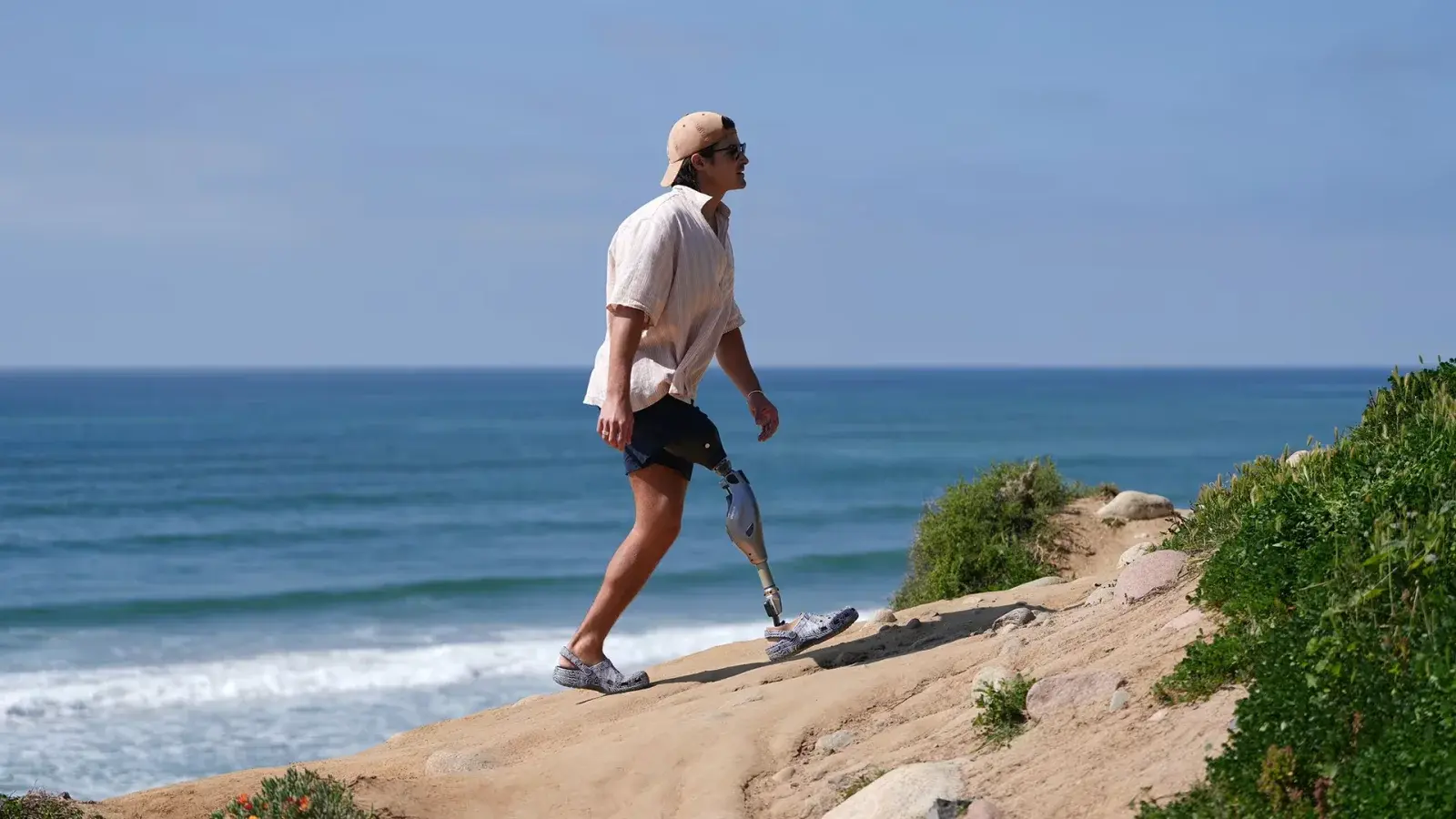 A person with a lower-limb prosthesis walking along a coastal path